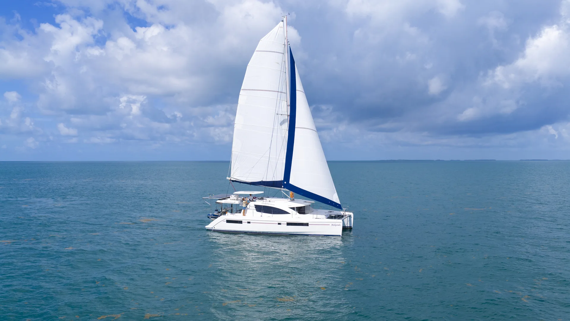 Sailing catamaran underway on clear Belize water