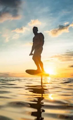 Guest riding an electric foil board at sunset
