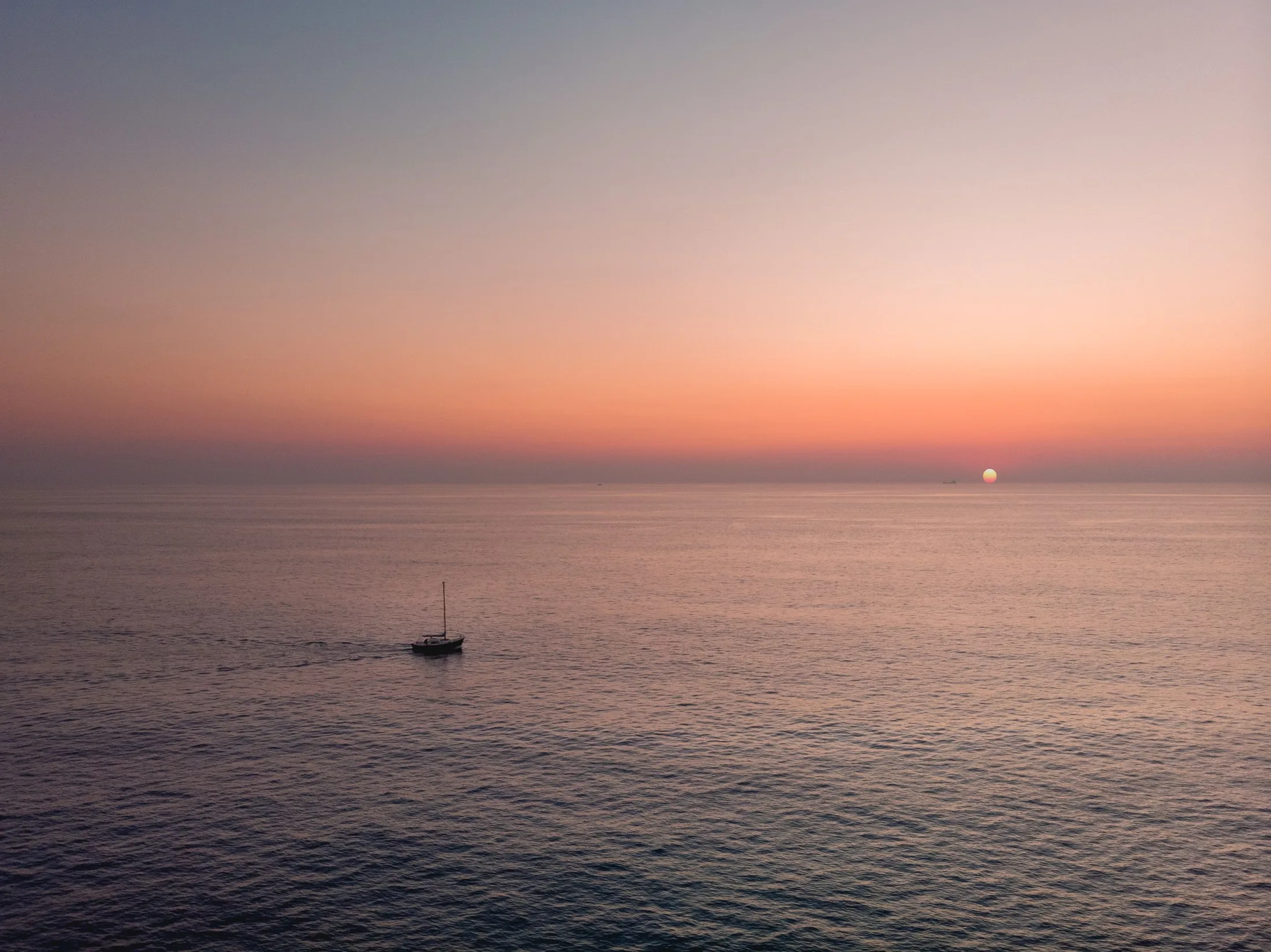 A lone yacht under a quiet sunset