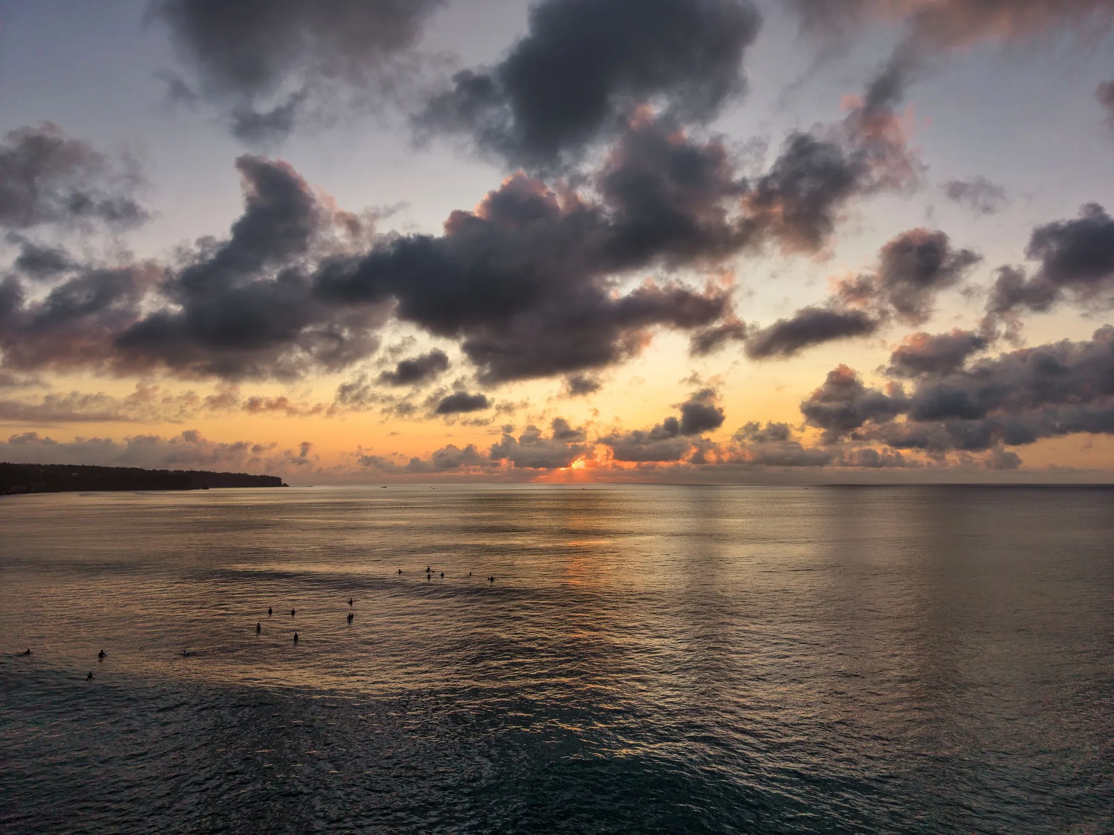 Paddleboarders on calm tropical water at sunset